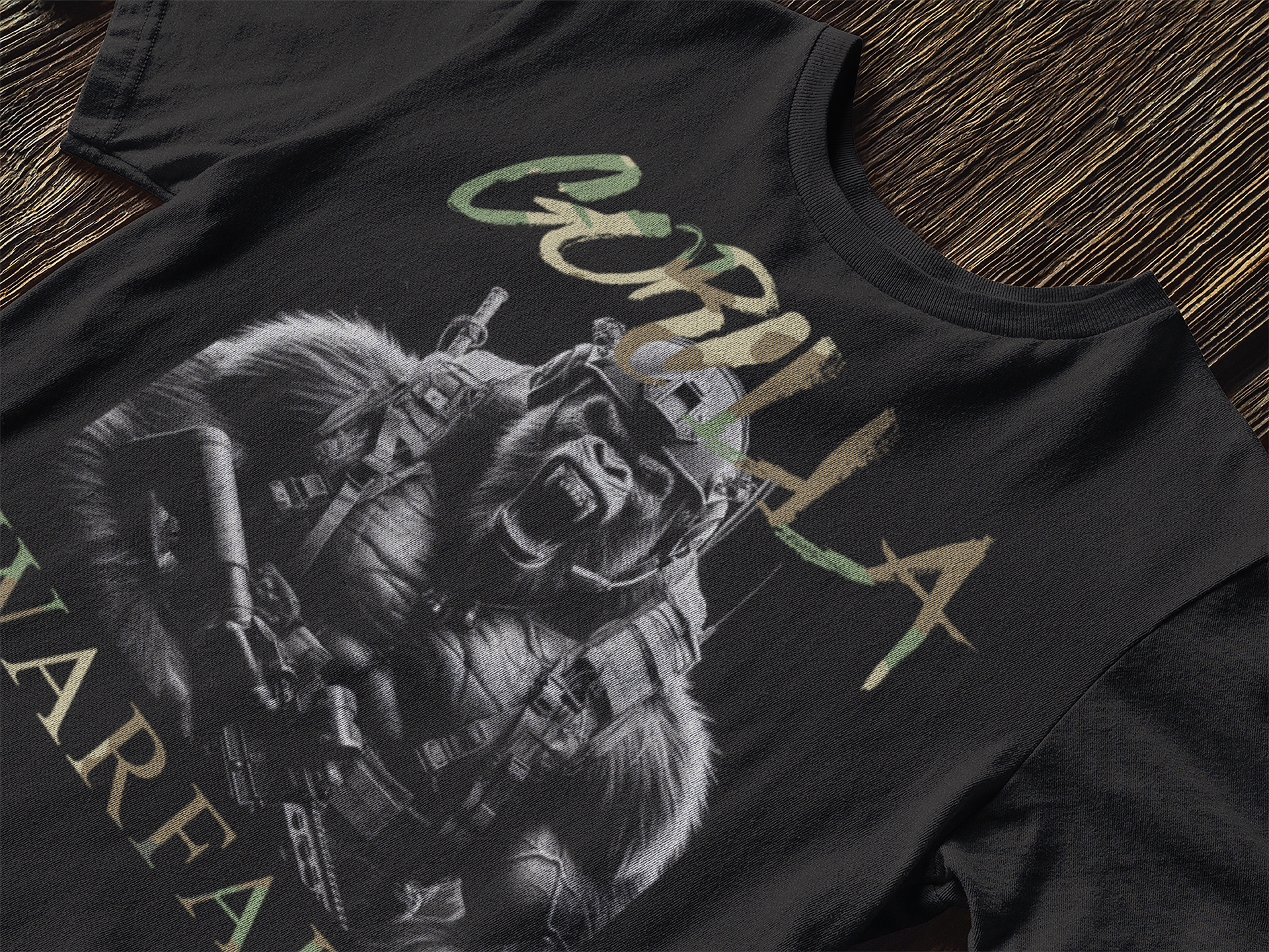 Close up view of the front of a black cotton short sleeve t-shirt on a wooden table by Achilles Tactical Clothing Brand with Gorilla warfare design printed across the front